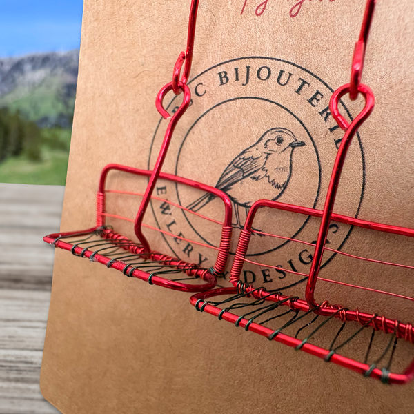 Red Chair wire jewelry display stands on a brown cardboard box with a jewelry store logo.