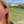 Close-up of a person wearing Red Chair earrings with a mountainous landscape in the background